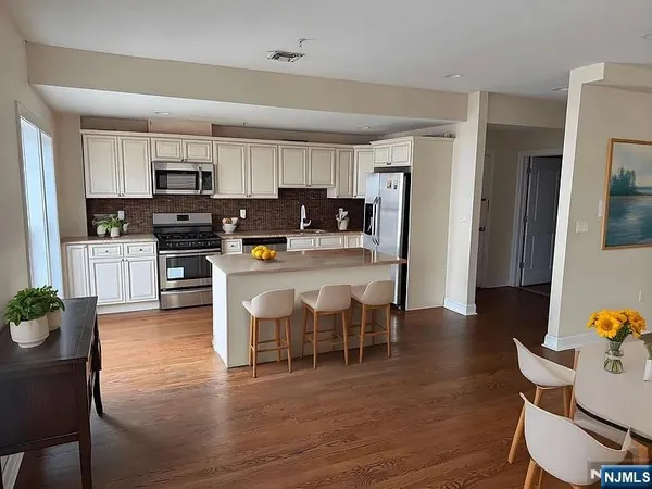 a kitchen with stainless steel appliances kitchen island wooden floors and view living room