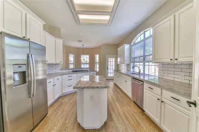 a large kitchen with stainless steel appliances granite countertop a sink refrigerator and cabinets