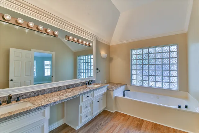 a spacious bathroom with a granite countertop tub a double vanity sink and a large mirror
