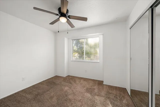 an empty room with a window and a fan