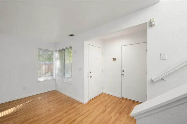 a view of an empty room with wooden floor and a window