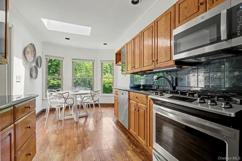 a kitchen with stainless steel appliances granite countertop a stove top oven a dining table and chairs with wooden floor