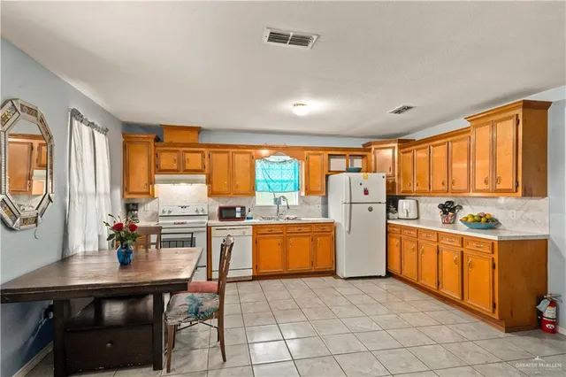 a kitchen with stainless steel appliances granite countertop a stove top oven a sink dishwasher and white cabinets with wooden floor