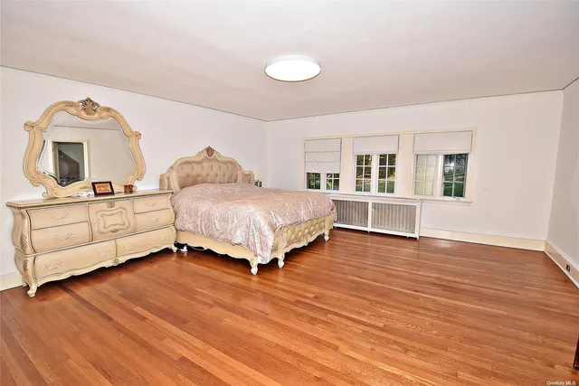 a spacious bedroom with a bed a dresser and next to a window