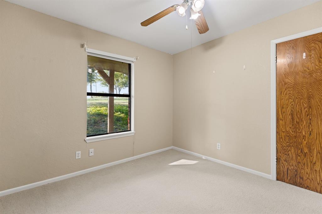 13539 Chapel Road Lorena, TX 76655 - Photo 19 of 37 Carpeted room with a ceiling fan, a window, and a wood-finish door