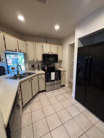 a kitchen with a refrigerator a stove top oven a sink and cabinets