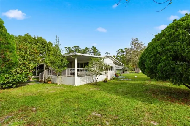 a view of a house with a big yard and large trees