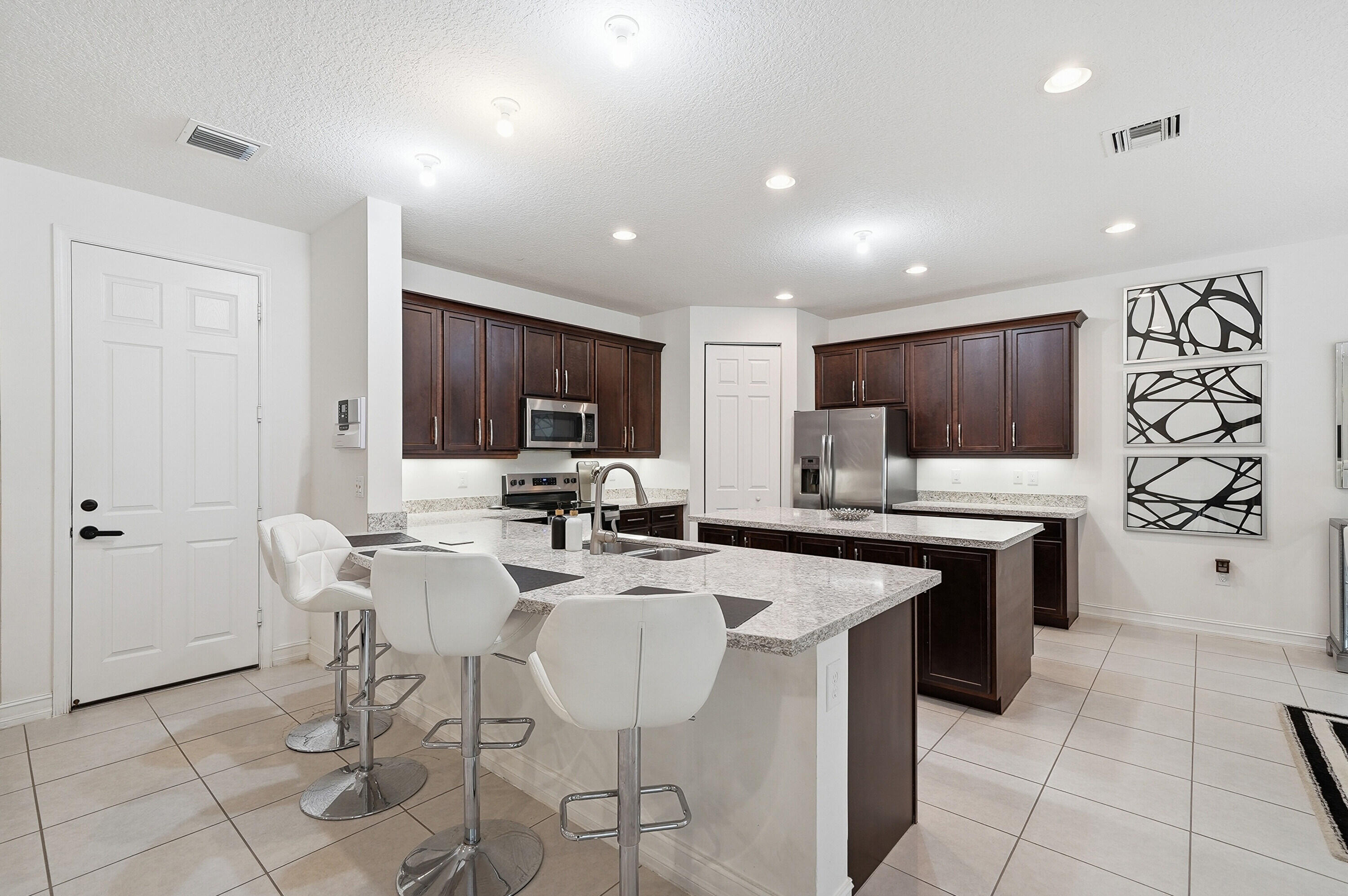14085 Paverstone Terrace Delray Beach, FL 33446 - Photo 9 of 46 a kitchen with stainless steel appliances granite countertop a table chairs sink and cabinets