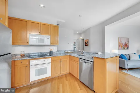 a kitchen with stainless steel appliances granite countertop a sink and cabinets with wooden floor