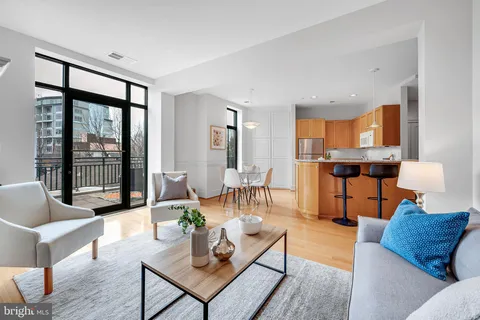 a living room with furniture kitchen view and a wooden floor