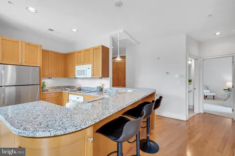 a kitchen with stainless steel appliances granite countertop a sink a refrigerator and a wooden cabinets