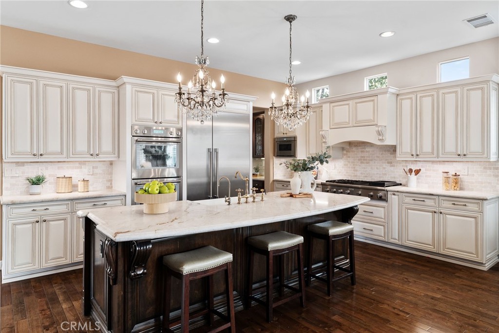6364 Hidden Brook Place Rancho Cucamonga, CA 91739 - Photo 22 of 61 a kitchen with kitchen island granite countertop a sink cabinets and wooden floor