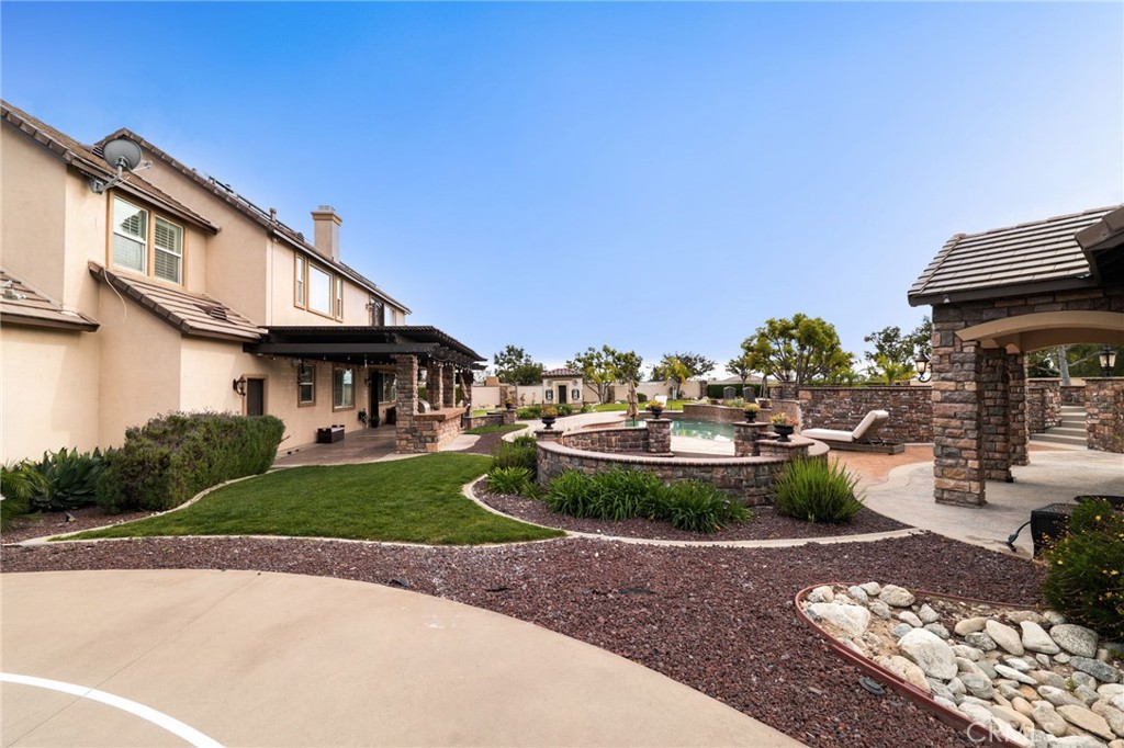 6364 Hidden Brook Place Rancho Cucamonga, CA 91739 - Photo 43 of 61 a view of a white house with a yard and table and chairs under an umbrella