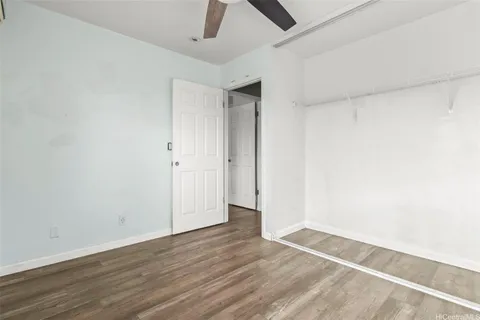 an empty room with wooden floor and ceiling fan