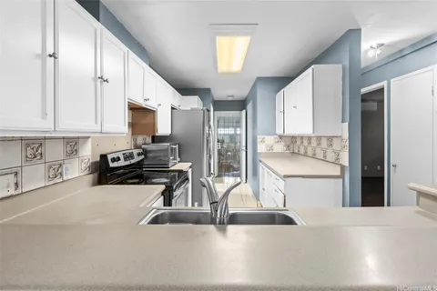 a kitchen with a sink a counter top space cabinets and stainless steel appliances