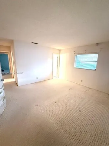 a view of an empty room with a window and fireplace