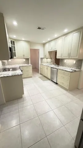 a large kitchen with granite countertop a large counter top and appliances