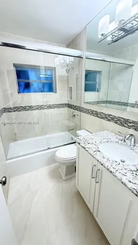 a bathroom with a granite countertop sink a toilet and bathtub