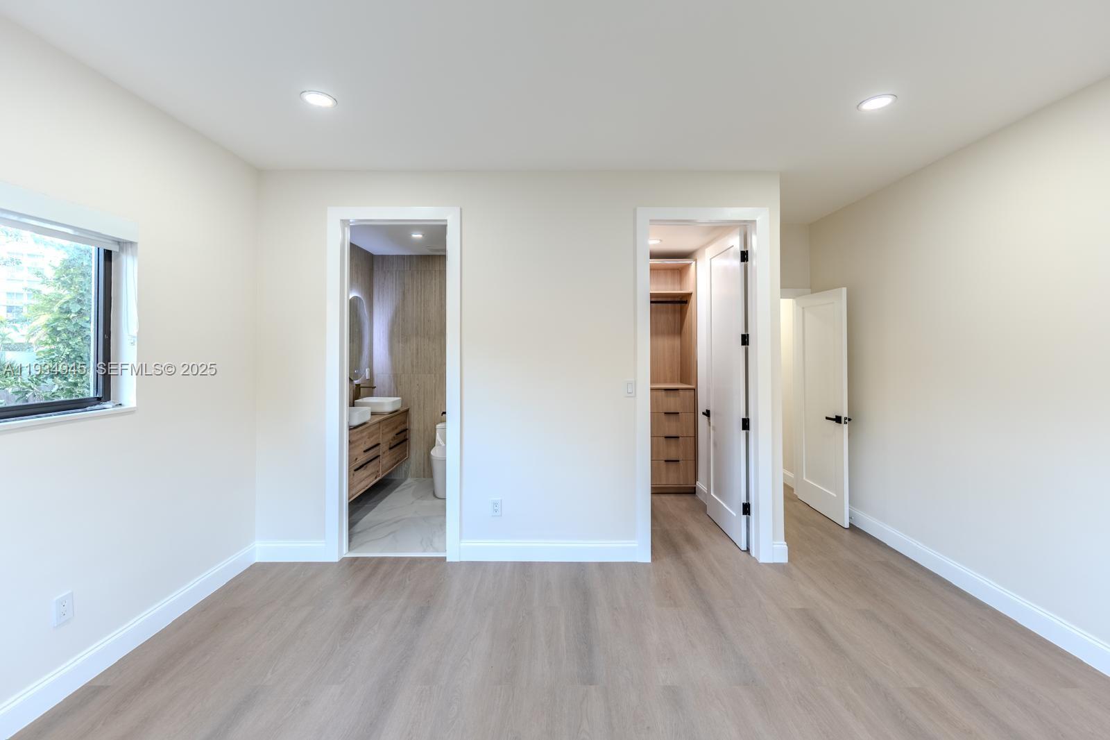 4144 Alton Road Miami Beach, FL 33140 - Photo 11 of 17 an empty room with wooden floor and windows