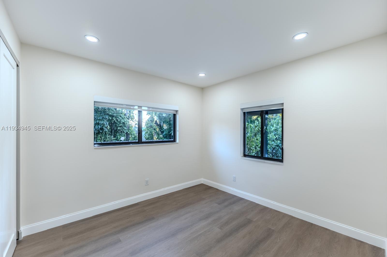 4144 Alton Road Miami Beach, FL 33140 - Photo 13 of 17 an empty room with wooden floor and windows