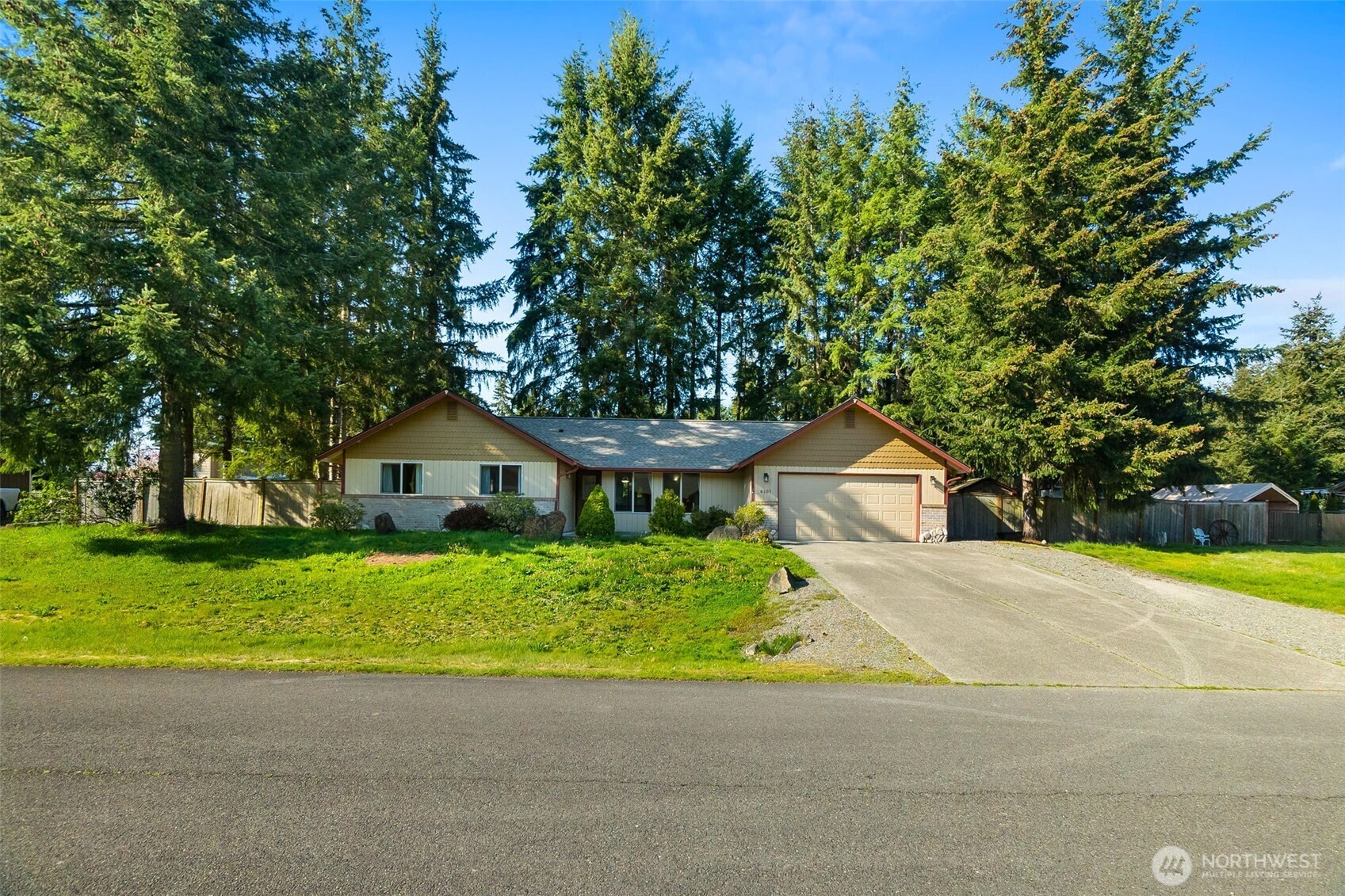 6107 189th Loop Southwest Rochester, WA 98579 - Photo 2 of 38 a front view of a house with a garden and trees