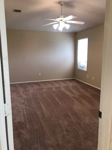 an empty room with windows and fan