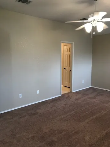 a view of an empty room with a chandelier fan