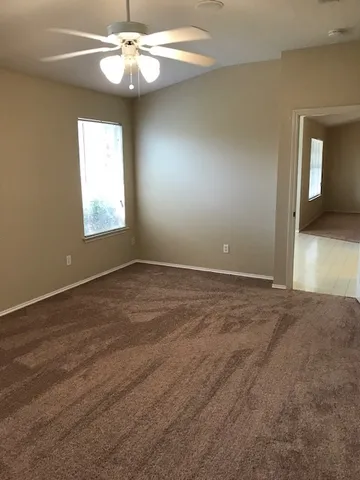 an empty room with a chandelier fan and windows
