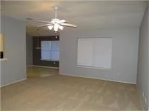 an empty room with a chandelier fan and windows
