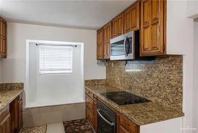 a kitchen with granite countertop a stove a sink and a microwave