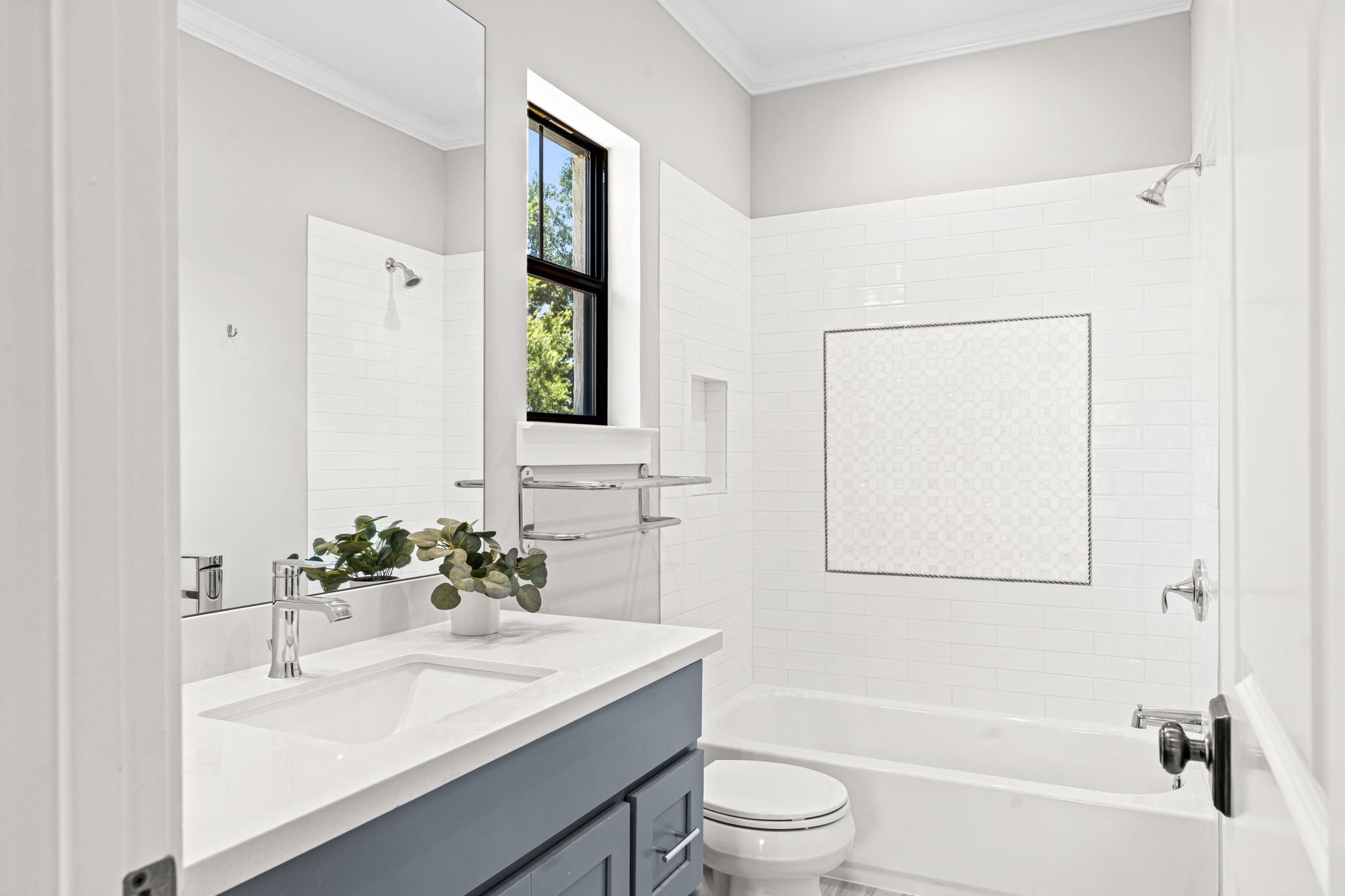 1013 Martin Street Houston, TX 77018 - Photo 30 of 46 Well-appointed en-suite bath for secondary bedroom #1 featuring a tub/shower combo w/ subway tile surround, decorative tile inlay, generous vanity storage, & direct access to an oversized walk-in closet.