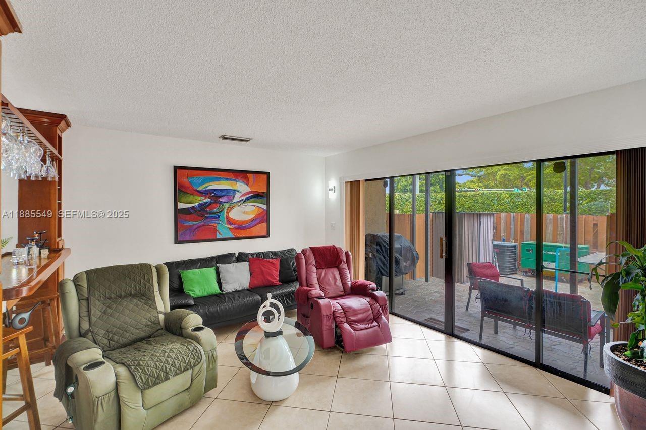 14201 Southwest 57th Lane, Unit 1A7 Miami, FL 33183 - Photo 14 of 48 a living room with furniture and a floor to ceiling window