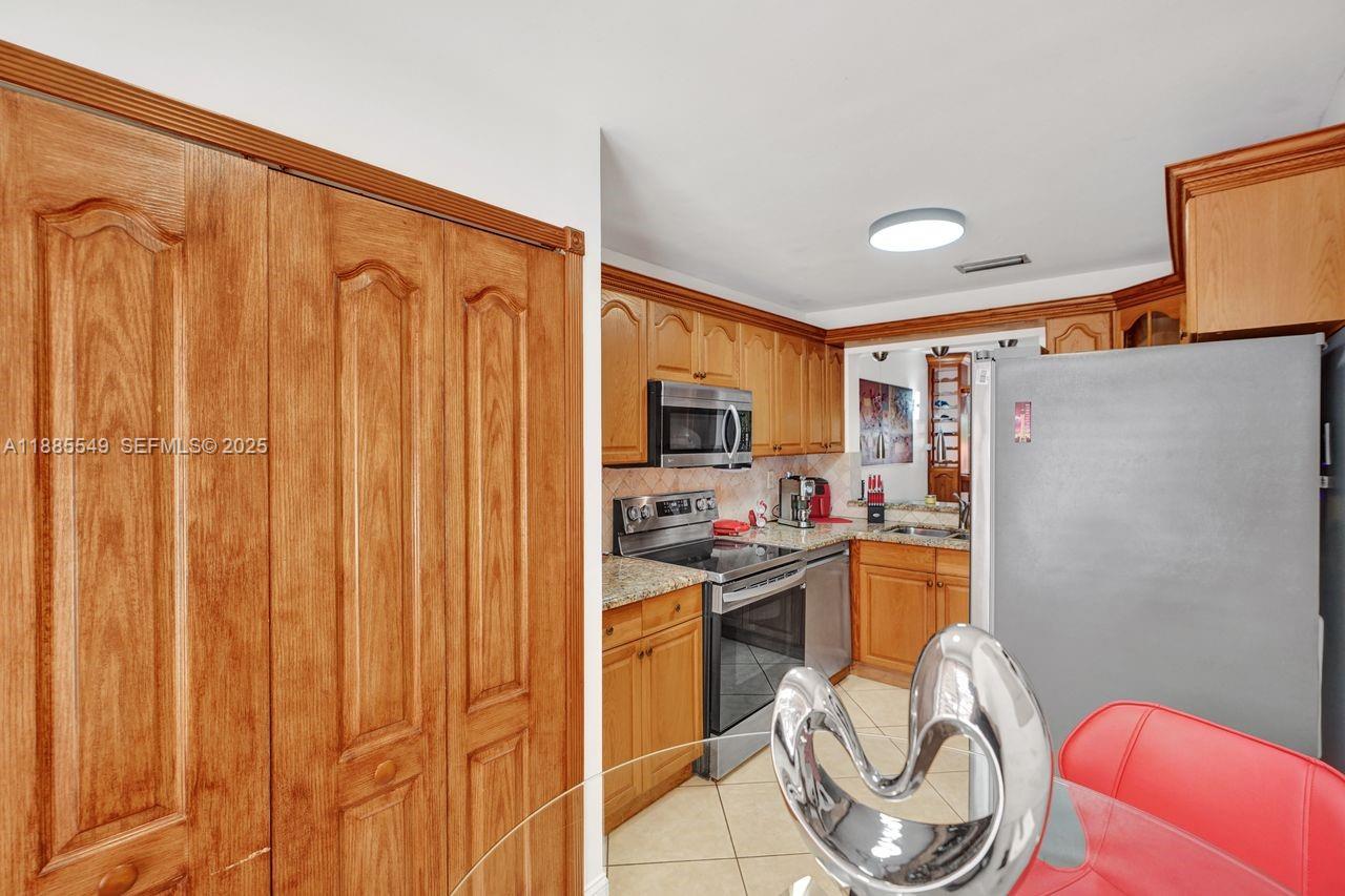 14201 Southwest 57th Lane, Unit 1A7 Miami, FL 33183 - Photo 22 of 48 a kitchen with stainless steel appliances granite countertop a refrigerator and a stove top oven