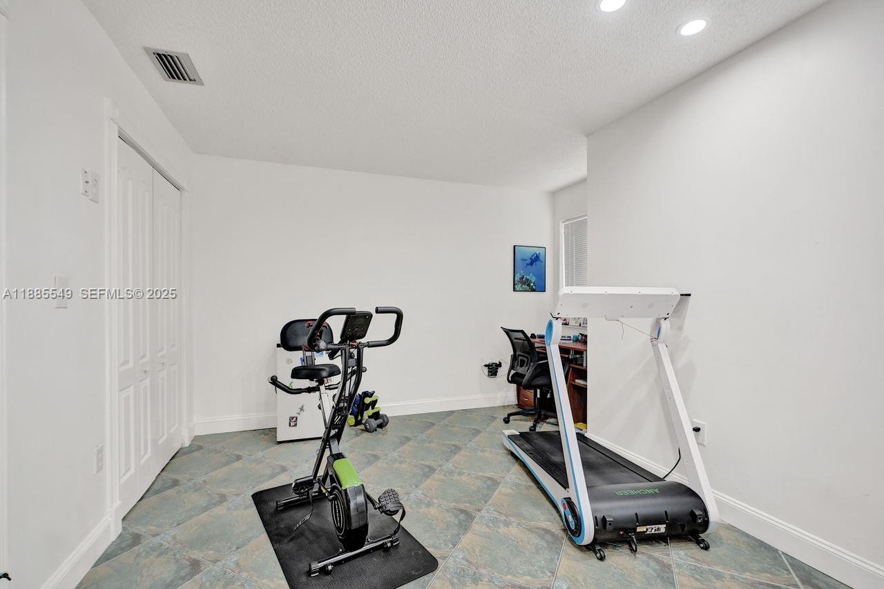 14201 Southwest 57th Lane, Unit 1A7 Miami, FL 33183 - Photo 30 of 48 a room with gym equipment and windows