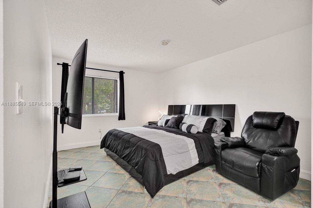 14201 Southwest 57th Lane, Unit 1A7 Miami, FL 33183 - Photo 34 of 48 a bedroom with a bed couch and a window
