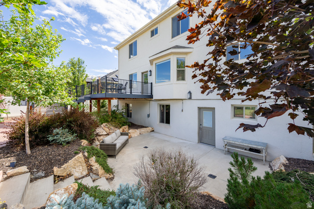 868 Braddock Lane Alpine, UT 84004 - Photo 56 of 64 Rear exterior featuring a raised deck with black railings, a ground-level concrete patio, and a bay window