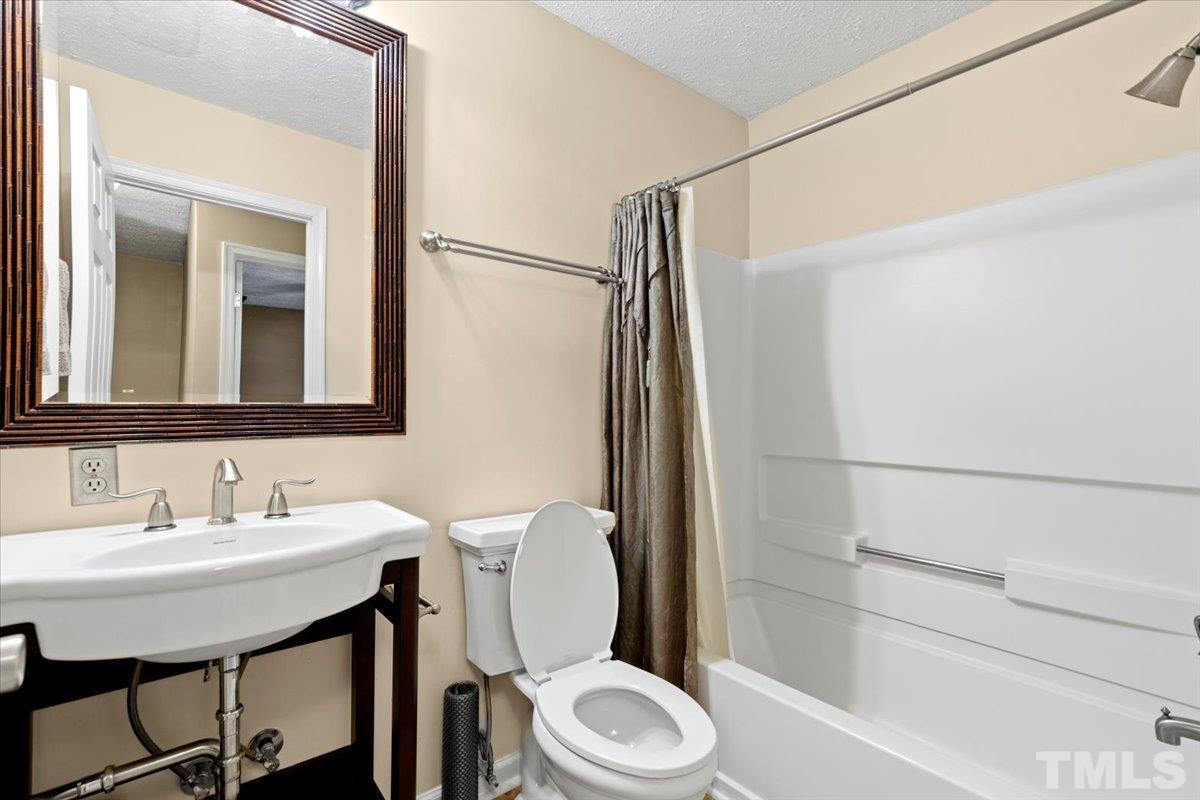 8224 Wynewood Court Raleigh, NC 27616 - Photo 25 of 29 a bathroom with a sink a toilet a mirror and shower