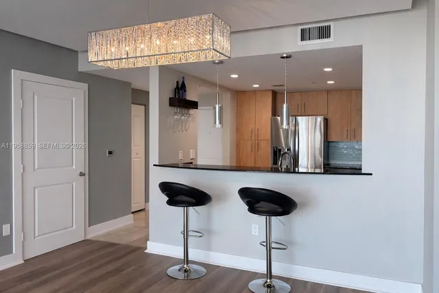 a kitchen with stainless steel appliances granite countertop a refrigerator a stove and a sink with wooden floor