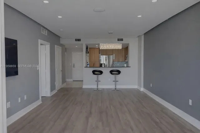 a view of an empty room with wooden floor and a fireplace