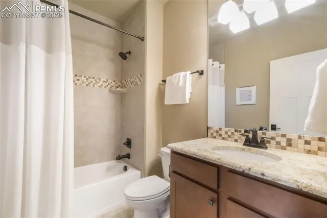 a bathroom with a granite countertop sink a toilet and shower
