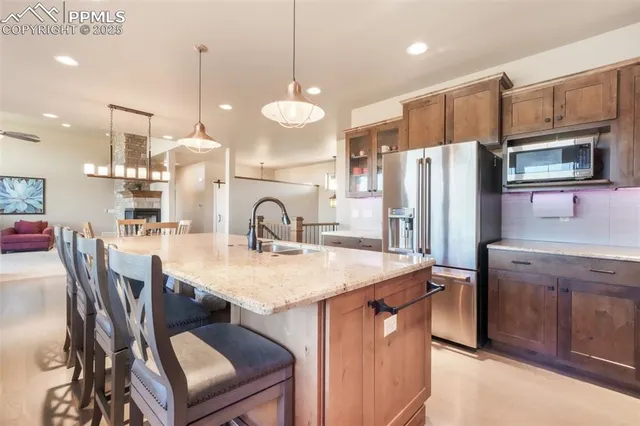 a kitchen with stainless steel appliances granite countertop a sink a stove a refrigerator a dining table and chairs