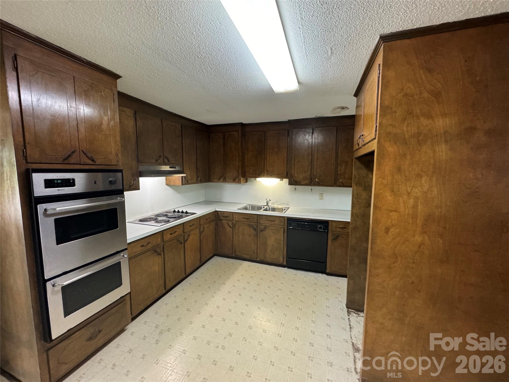 509 East Main Street Locust, NC 28097 - Photo 11 of 40 a kitchen with stainless steel appliances kitchen island granite countertop a refrigerator a stove and a sink with wooden floor