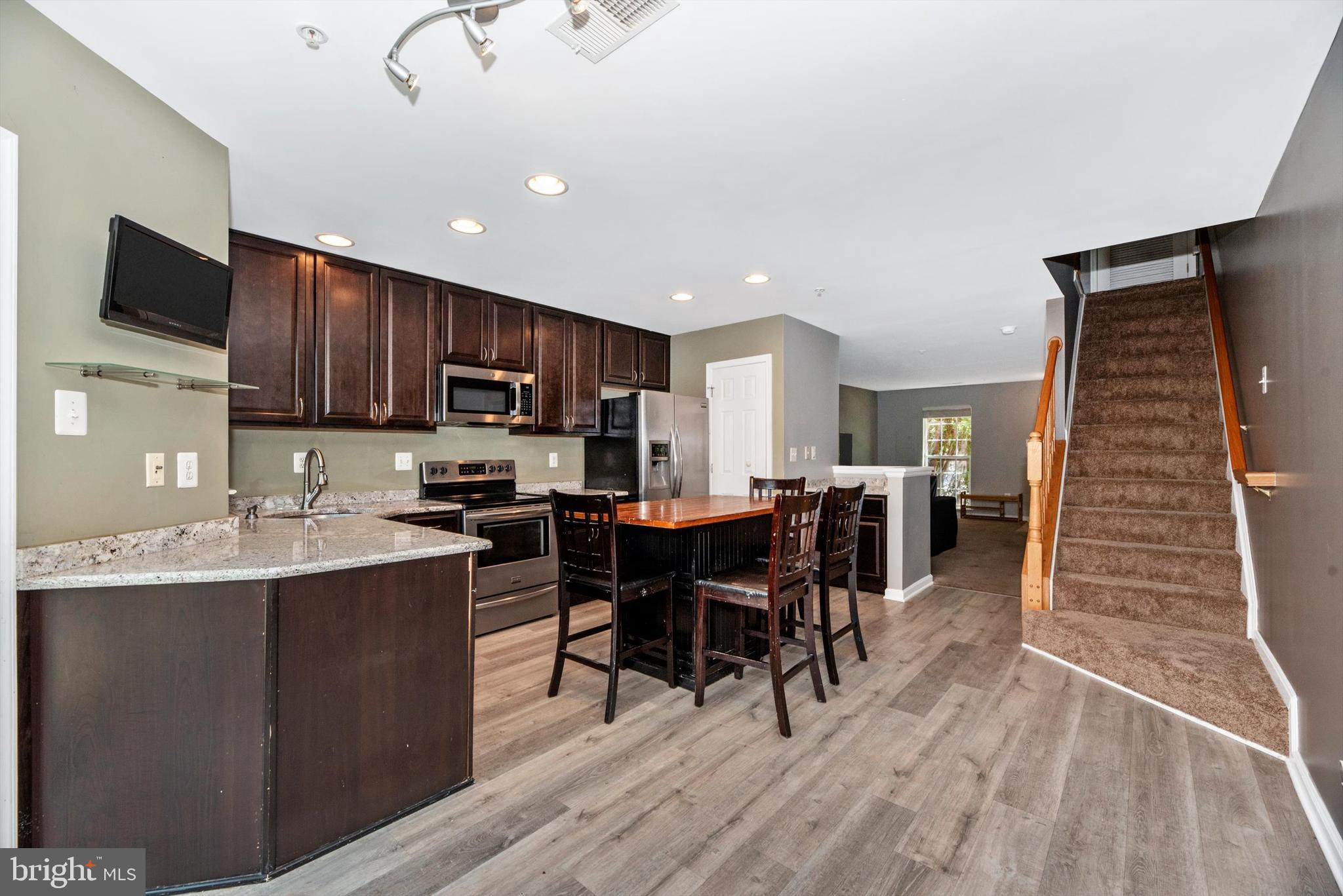 605 Tivoli Road Frederick, MD 21703 - Photo 8 of 35 a kitchen with stainless steel appliances granite countertop a refrigerator a stove top oven a sink dishwasher a dining table and chairs with wooden floor