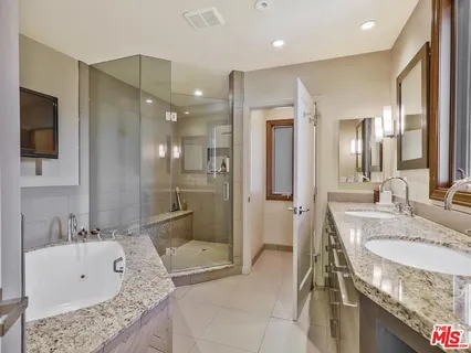 a bathroom with a granite countertop tub sink and mirror