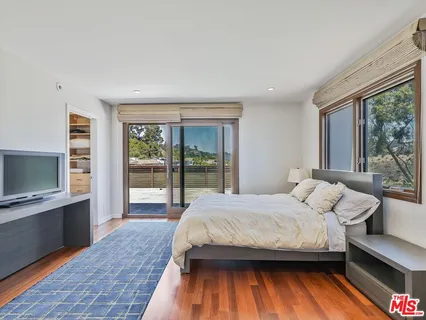 a bedroom with a bed and large windows