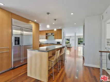 an open kitchen with kitchen island wooden floor and refrigerator