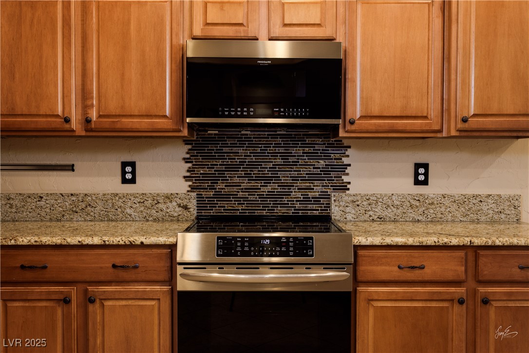 1074 Wagon Trail Mesquite, NV 89034 - Photo 11 of 27 Kitchen with brown cabinets, light stone counters, tasteful backsplash, and appliances with stainless steel finishes