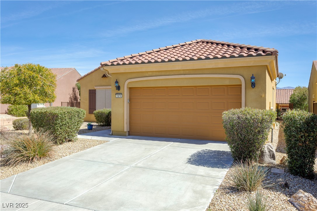 1074 Wagon Trail Mesquite, NV 89034 - Photo 27 of 27 Mediterranean / spanish-style house with stucco siding, driveway, a tiled roof, and an attached garage