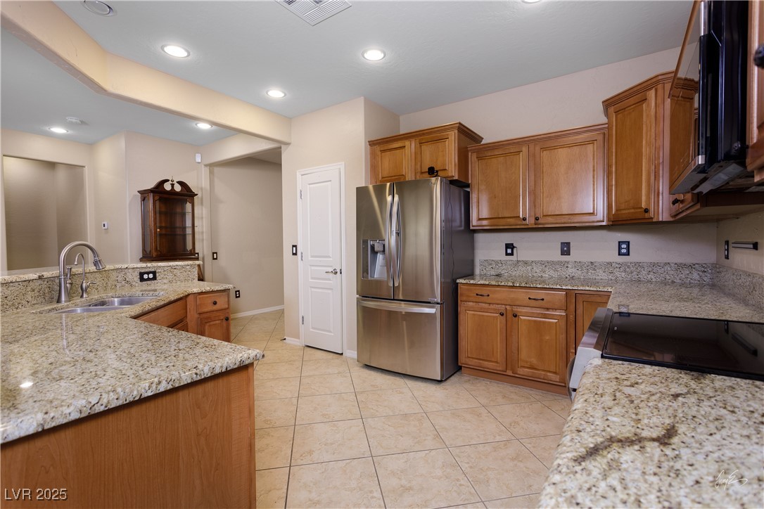 1074 Wagon Trail Mesquite, NV 89034 - Photo 9 of 27 Kitchen featuring visible vents, a sink, stainless steel refrigerator with ice dispenser, brown cabinetry, and light tile patterned floors
