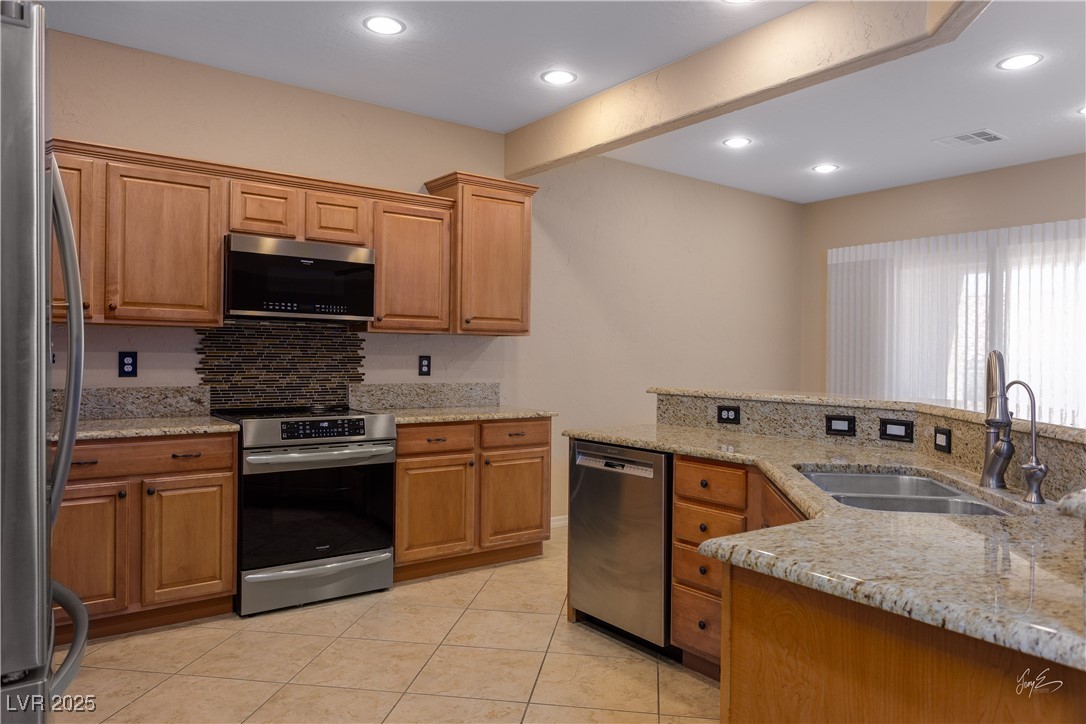 1074 Wagon Trail Mesquite, NV 89034 - Photo 10 of 27 Kitchen featuring light tile patterned floors, a sink, light stone counters, visible vents, and appliances with stainless steel finishes